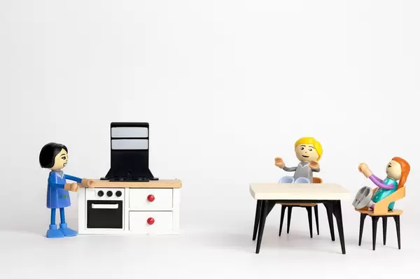 Kinder an einem Tisch warten auf das Abendessen mit der Mutter in der Küche - Modelfiguren