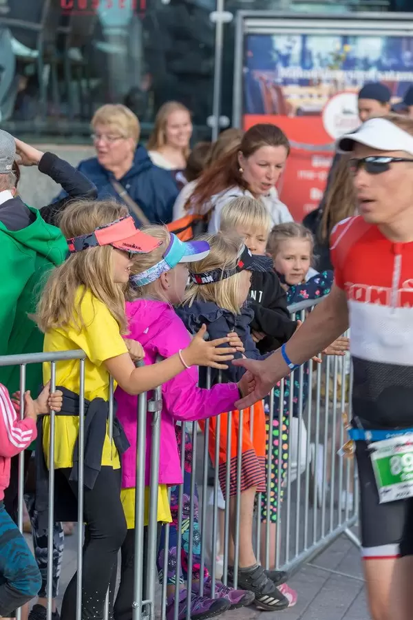Kinder gratulieren Marathonläufer mit High-Fives kurz vorm Ziel beim Ironman 70.3 Triathlon in Lahti, Finnland