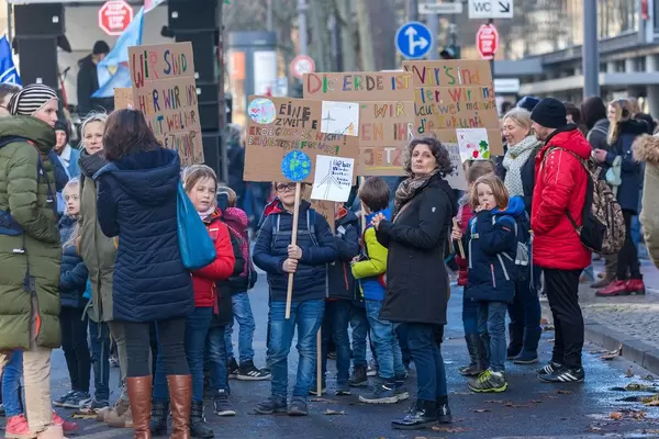 Kinder mit Ihren Eltern nehmen am Klimastreik teil und halten Demoschilder in die Luft