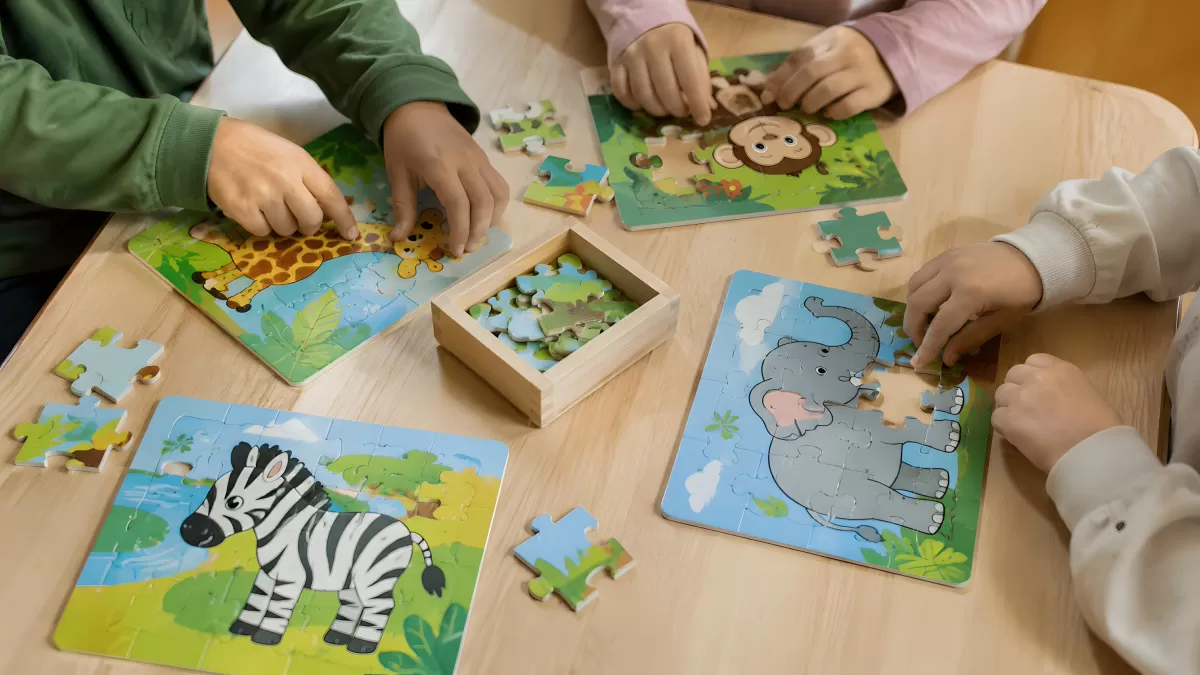 Kinder puzzeln gemeinsam Tiere am Holztisch