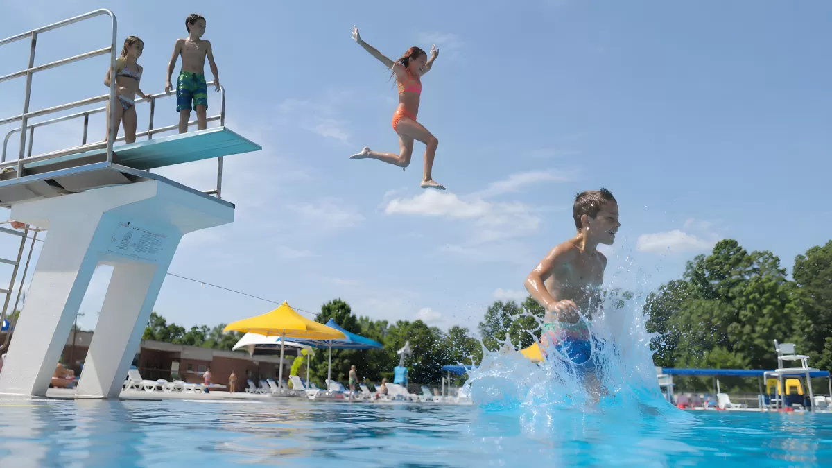 Kinder springen vom Sprungbrett ins Freibad