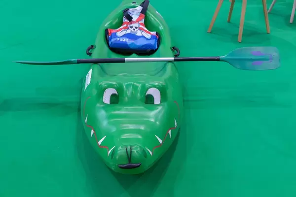 Kinderkanu in Form eines grünen Krokodils mit Paddel und Schwimmweste mit Piratenmotiv