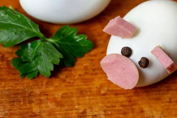 Kindermahlzeit - Ein Ei als Schweinchen mit Wurst als Nase und Ohren