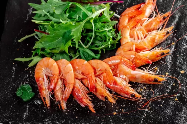 King prawns with fresh arugula leaves on black background (Flip 2019)