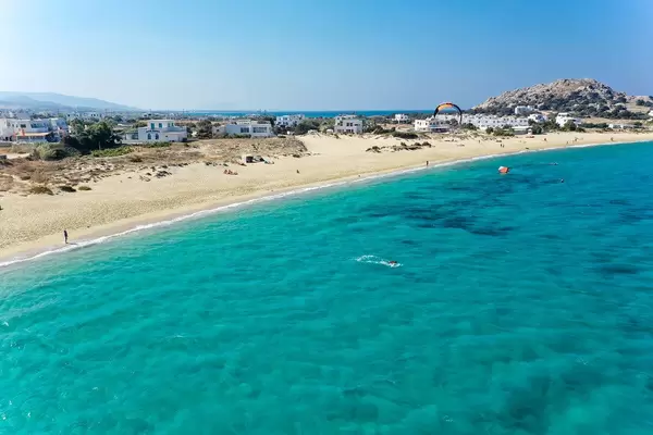 Kite surfing in the blue waters of Naxos at Mikri Vigla beach. Aerial view with headland and village