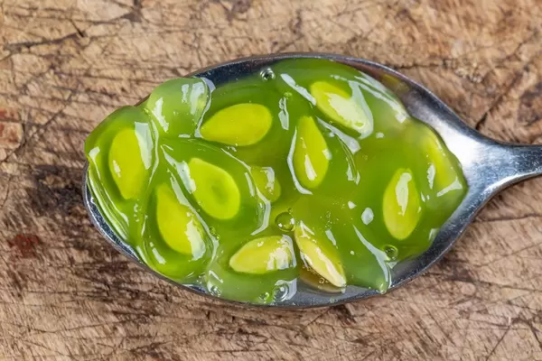 Kiwano pulp and seeds in a spoon on a wooden background, top view