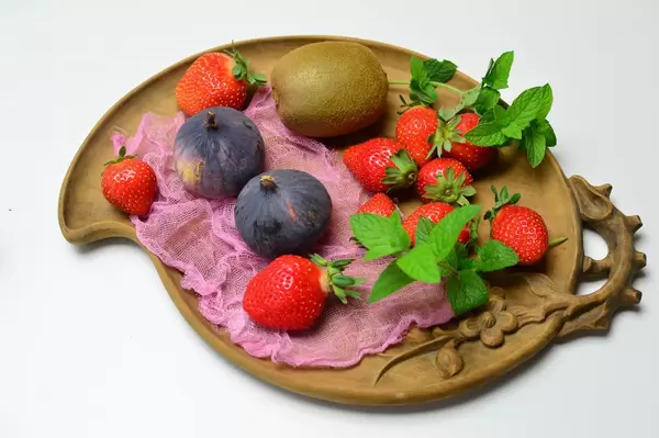 Kiwi mit Feigen und Erdbeeren auf Tonteller mit Pfefferminzblättern garniert