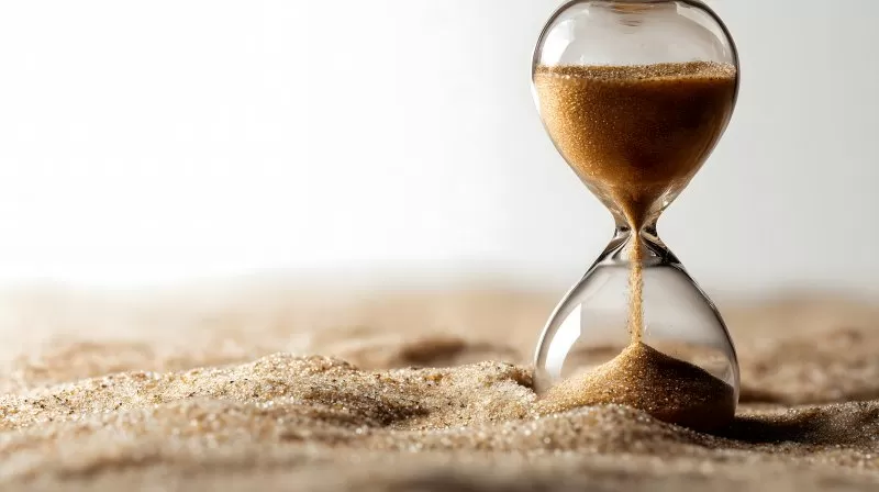 Klassische Sanduhr im Sand als Symbol für Zeitverlauf