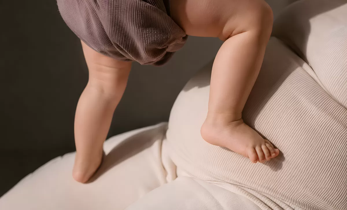Kleine Babybeine stehen auf hellem Sofa