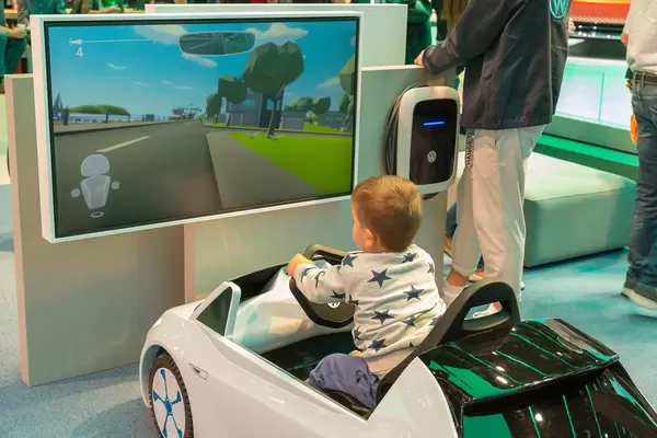 Kleine Fahrschule: Kleinkind im Spielzeugauto von Volkswagen, beim E-Mobilitäts-Fahrsimulator, Videospiel auf der IAA