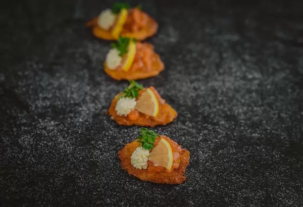 Kleine Kartoffelpuffer garniert mit Kresse, Zitrone, roten Kaviar und Mayonnaise - vertikale Nahaufnahme