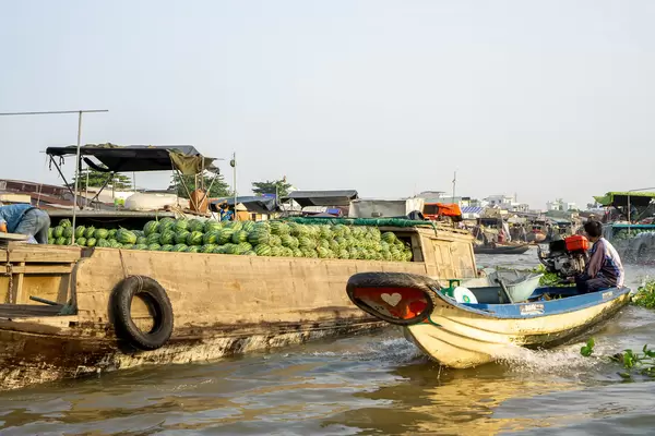 Kleine Schiffe und Boote verkaufen verschiedene Früchte wie Wassermelonen und andere Waren auf dem Cai Rang Schwimmenden Markt in Can Tho, Vietnam