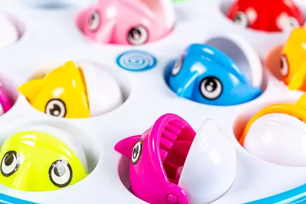 Kleine Spielzeugfische öffnen ihr Maul um aus einem Plastik Behälter geangelt zu werden - Kinderspiel