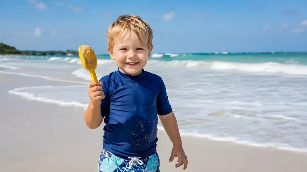 Kleiner Junge mit Schaufel am Strand im Sommer