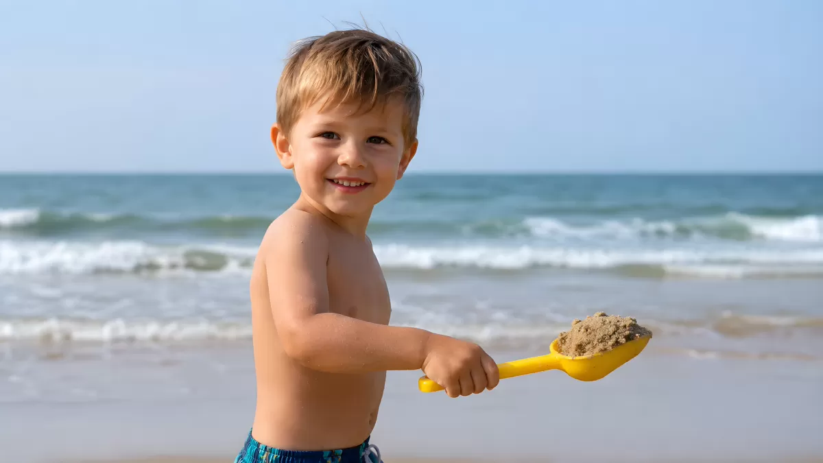 Kleiner Junge spielt mit Schaufel am Strand
