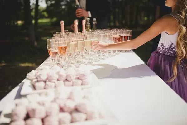 Kleines Mädchen im festlichen Kleid greift nach einem Sektglas