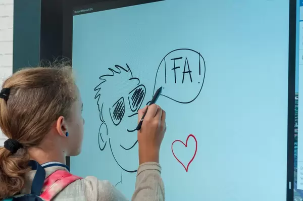 Kleines Mädchen zeichnet mit einem Stylus auf einem große Bildschirm