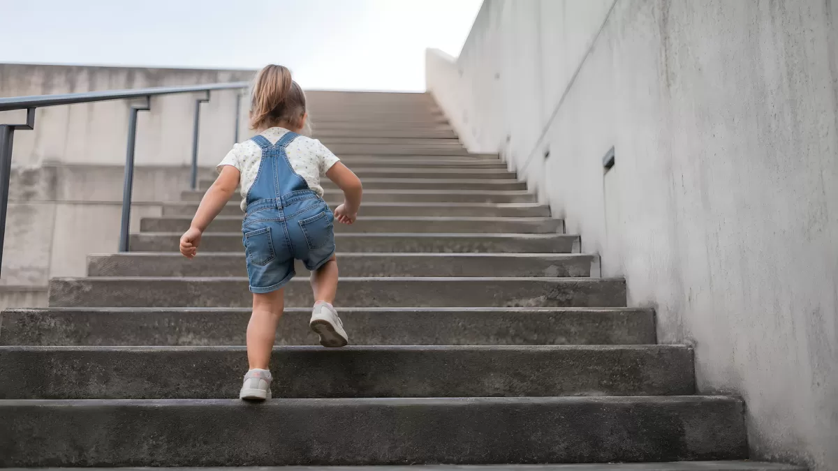 Kleinkind klettert alleine eine Betontreppe hinauf