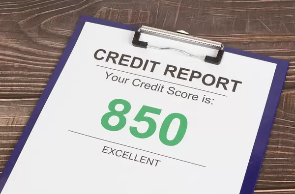 Klemmbrett mit Kreditscore-Bericht mit ausgezeichnetem Kreditscore-Ergebnis von 850 auf einem Holztisch