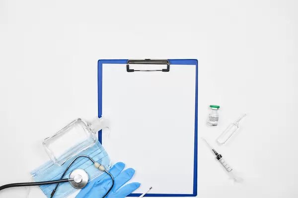 Klemmbrett mit Platz für Text, Desinfektionsmittel, Einmalhandschuh, OP-Maske, Stethoskop, Spritze, Ampullen