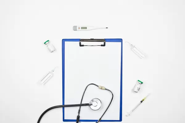 Klemmbrett und Medizinbedarf vor weißem Hintergrund mit Platz für Text