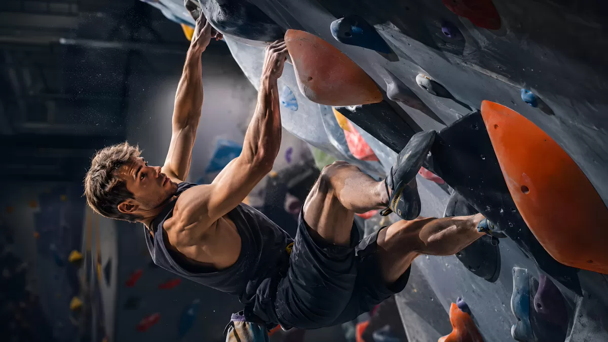Kletterer an überhängendem Boulderproblem in der Halle