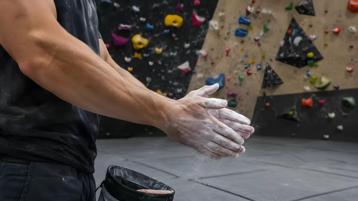 Kletterer chalk seine Hände in der Boulderhalle