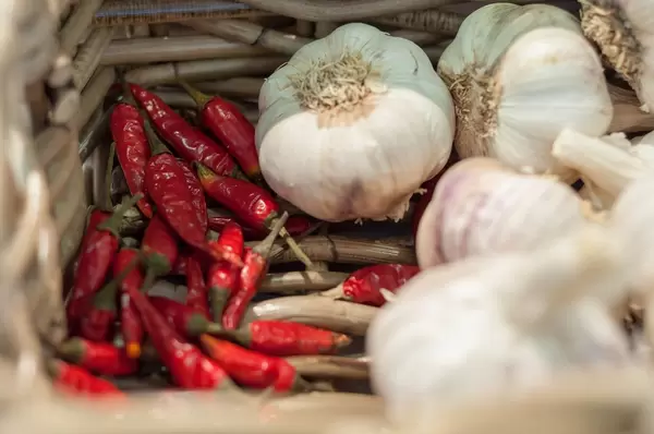 Knoblauchknollen und getrocknete Chilischoten in einem geflochtenen Korb