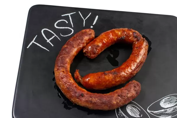 Knusprig gebratene Würste auf schwarzem Küchenbrett mit Aufschrift TASTY