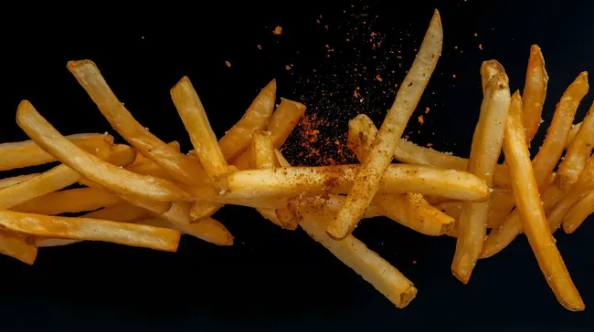 Knusprige Pommes mit Gewürzen vor dunklem Hintergrund