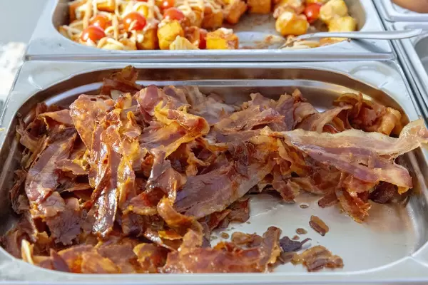 Knuspriger Speck in einem Warmhaltebehälter an einem Buffet