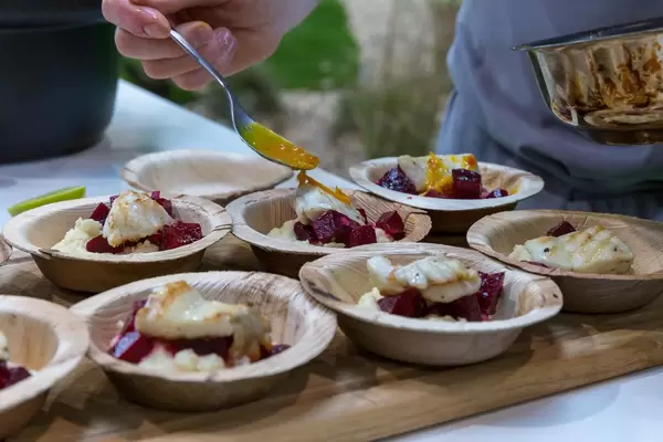 Koch bereitet Probierportionen vor und verfeinert Fischgericht mit Soße