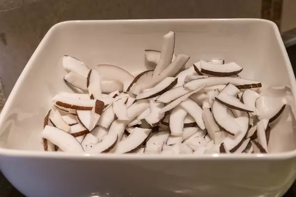 Kokosnuss mit Schale in Streifen geschnitten in einer weißen Schale