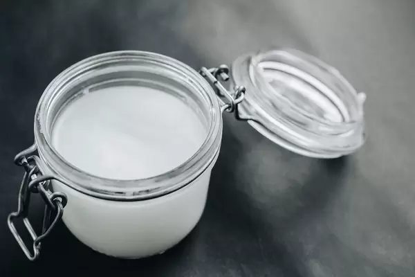 Kokosnussöl im Glas vor dunklem Hintergrund