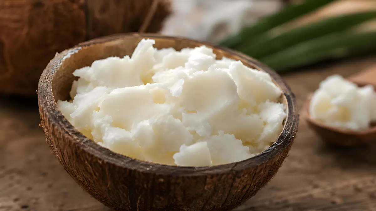 Kokosöl in einer Kokosnussschale auf Holztisch