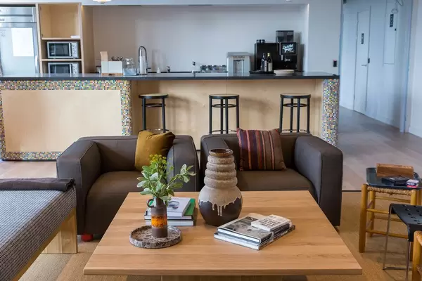 Kölner WeWork-Aufenthaltsraum mit Sitzmöglichkeiten im Wohnzimmer mit Sesseln und Gemeinschaftsküche mit Barhocker