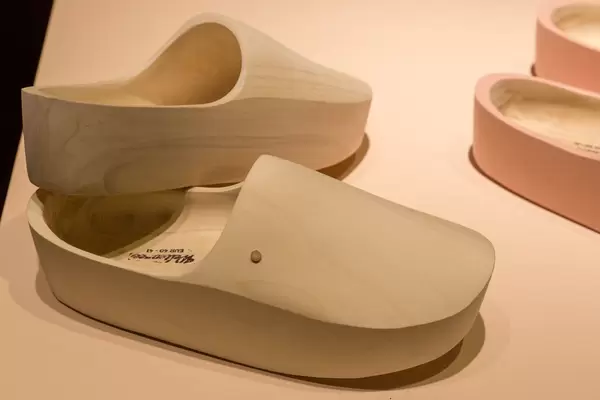 Komplett aus Holz gefertigte Pantoletten mit dicker Sohle auf beigem Untergrund