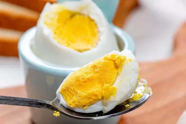 Konzept Frühstück: ein gekochtes Ei löffeln