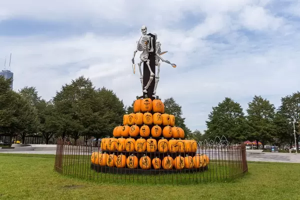 Konzept Hexenverbrennung: Skelette als gruselige Halloweendekoration an einem Pfahl, mit Kürbissen als Feuerstelle