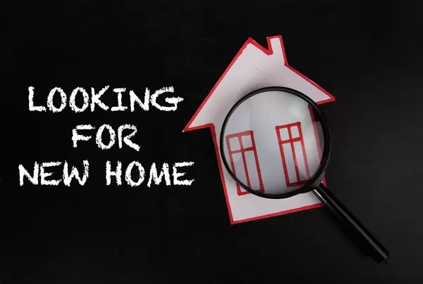 Haussuche - Gebasteltes Haus unter Lupe