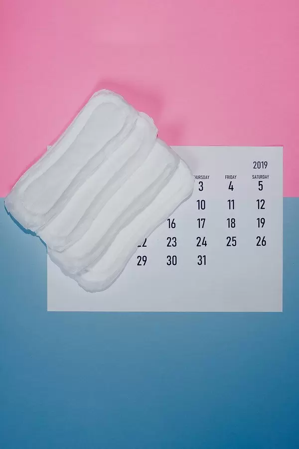 Konzeptbild zum Thema Menstruationszyklus, zeigt Damenbinden auf einem Kalender, aus der Sicht von oben