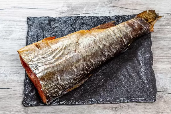 Kopfloser Räucherlachs auf einem schwarzen Brett in obene Aufnahme