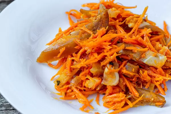 Koreanische Karotten mit Stücken von geräucherten Schweinefleischohren auf weißem Teller