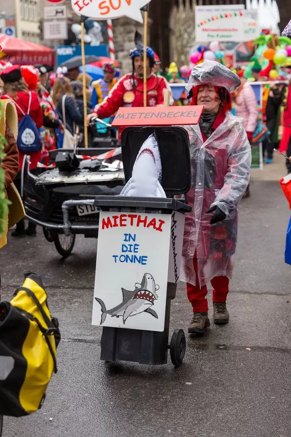 Kostümierte Frau der Pappnasen-Rotschwarz mit Miethai in einer Mülltonne beim Rosenmontagszug in Köln