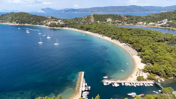 Koukounaries Marina with boats docked and famous Koukounaries beach on Skiathos, Greece