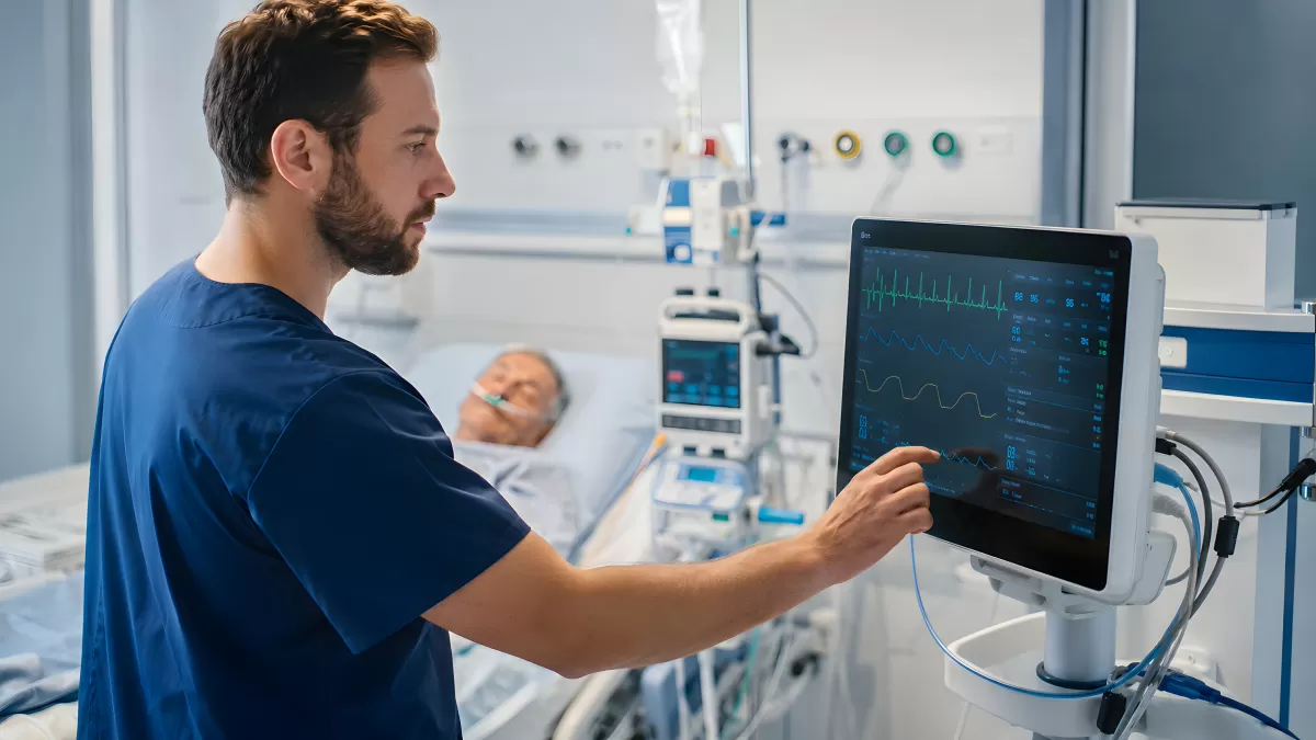Krankenpfleger überwacht Patientenmonitor auf Intensivstation