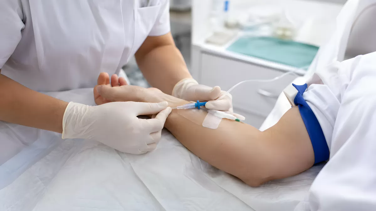 Krankenschwester legt Venenkatheter am Arm eines Patienten
