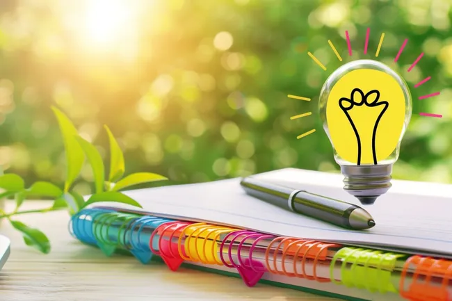 Kreative Idee - Glühbirne auf Schreibtisch mit Büromaterial