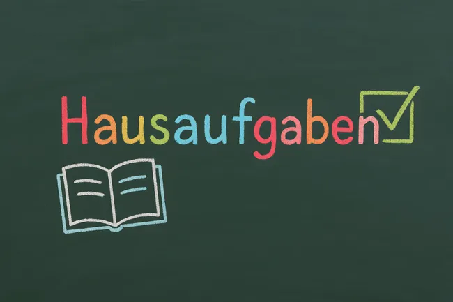 Kreide-Tafel mit Hausaufgaben-Aufgabe und Häkchen-Symbol