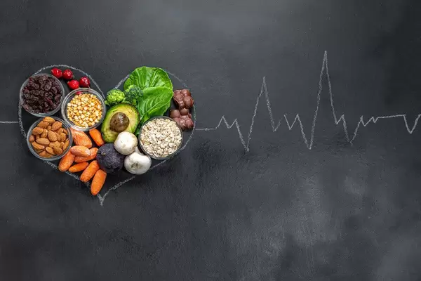 Kreideherz gefüllt mit gesunden Lebensmitteln und Pulsschlag auf schwarzer Tafel